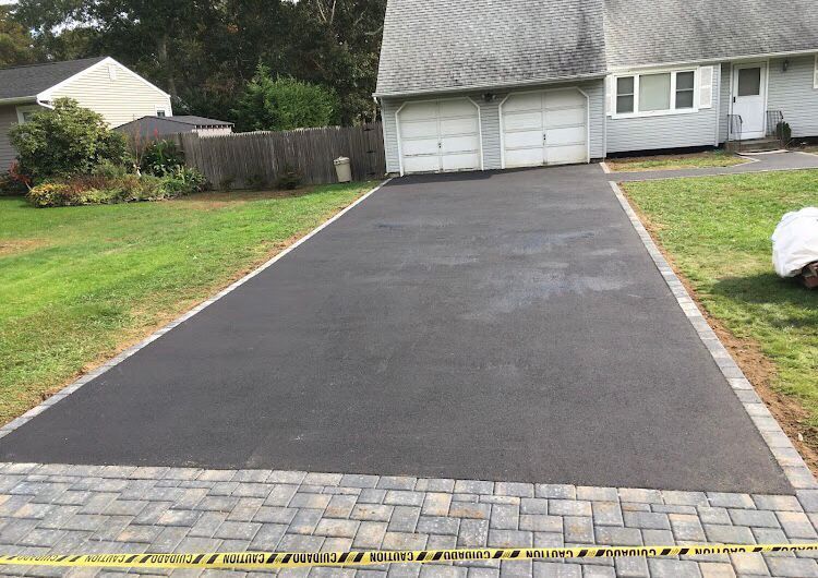 A brick driveway leading to a house with two garage doors.