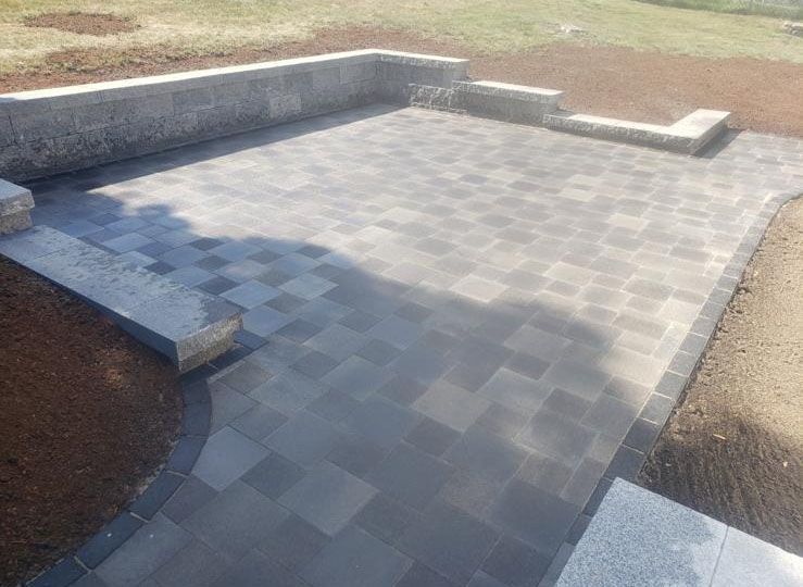 A patio with a stone wall and steps leading to it.
