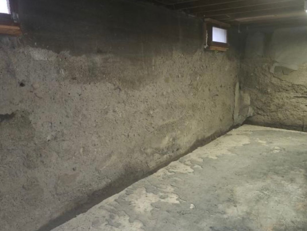 A basement with a concrete floor and a concrete wall.