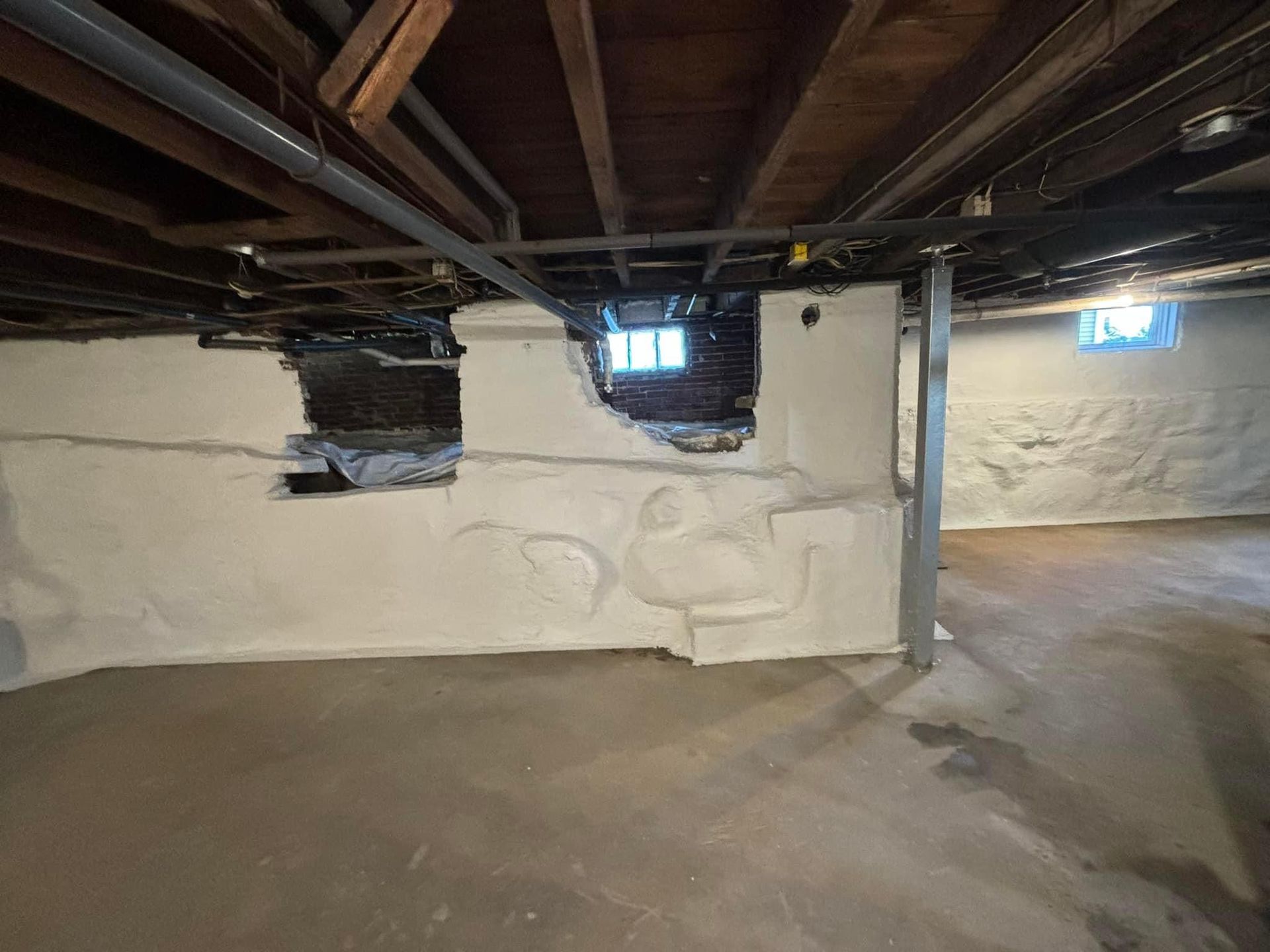 A basement with a hole in the wall and a window.