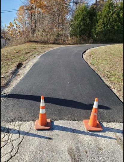 Two orange traffic cones are sitting on the side of a road.