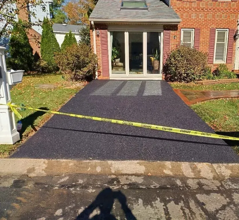 A brick house with a sliding glass door and a black driveway