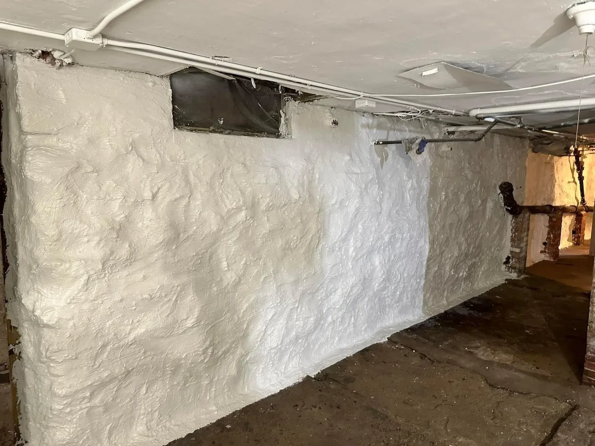 A wall in a basement is covered in white foam.