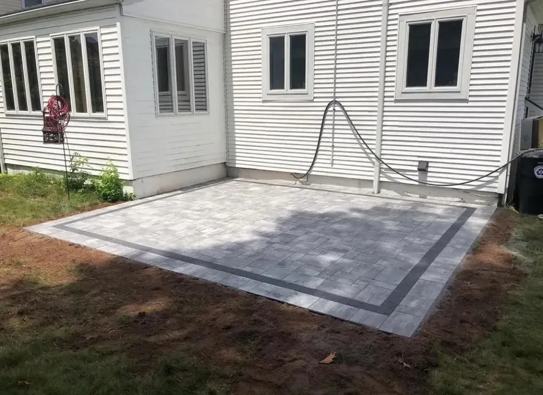 A patio is being built in the backyard of a house.