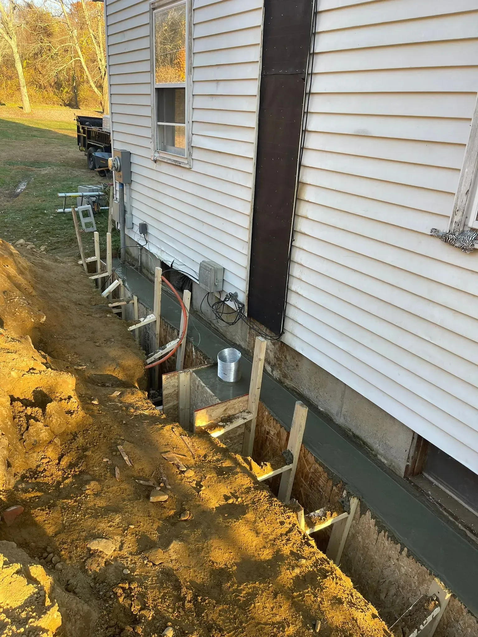 A house is being remodeled with concrete being poured on the side of it.
