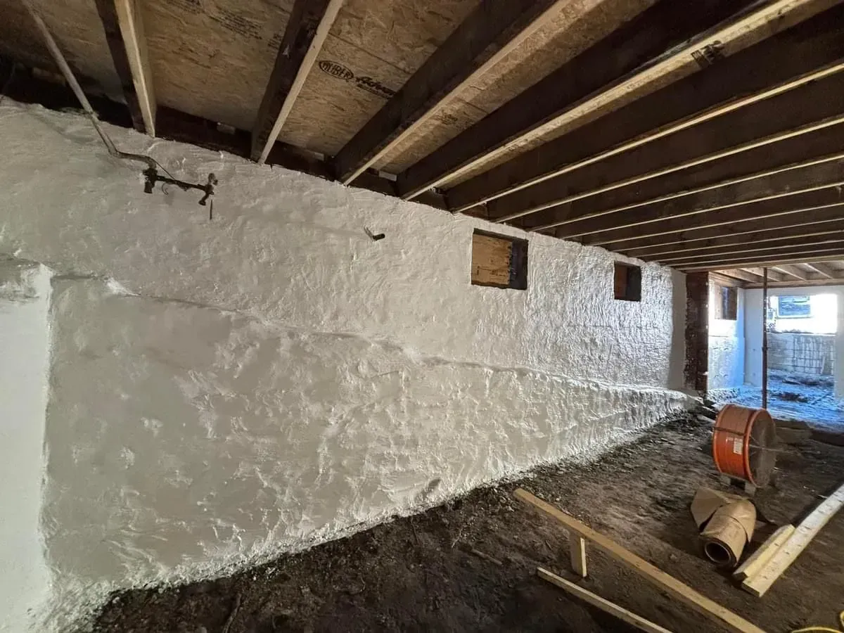 A basement with a white wall and a wooden ceiling.