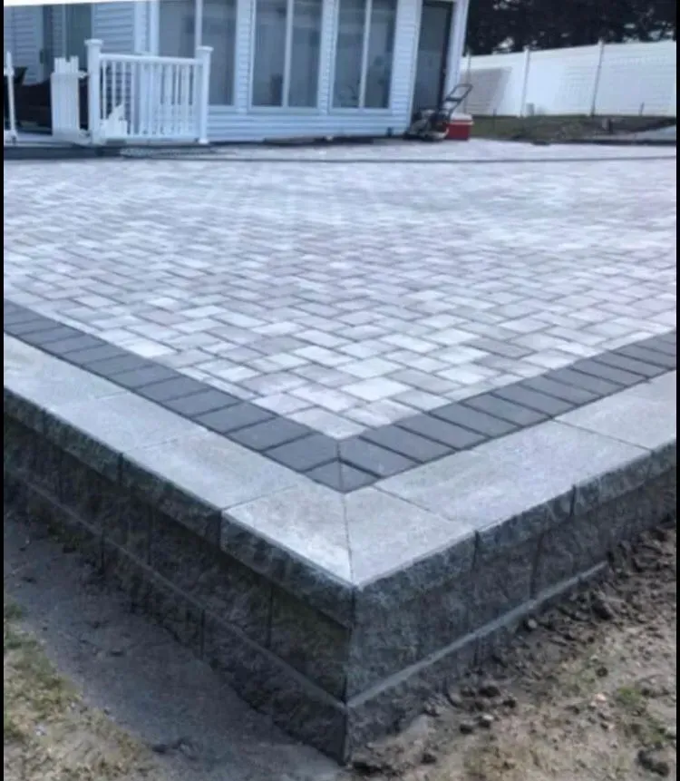 A brick driveway with a brick wall in front of a house.