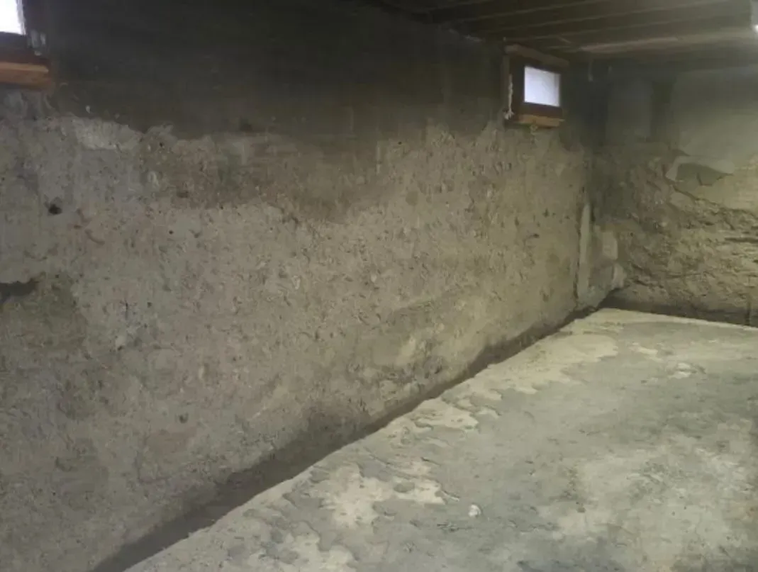 A concrete basement with a window and a concrete floor.