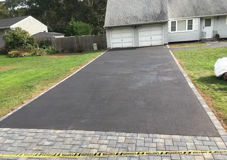 A driveway with a brick walkway leading to a house.