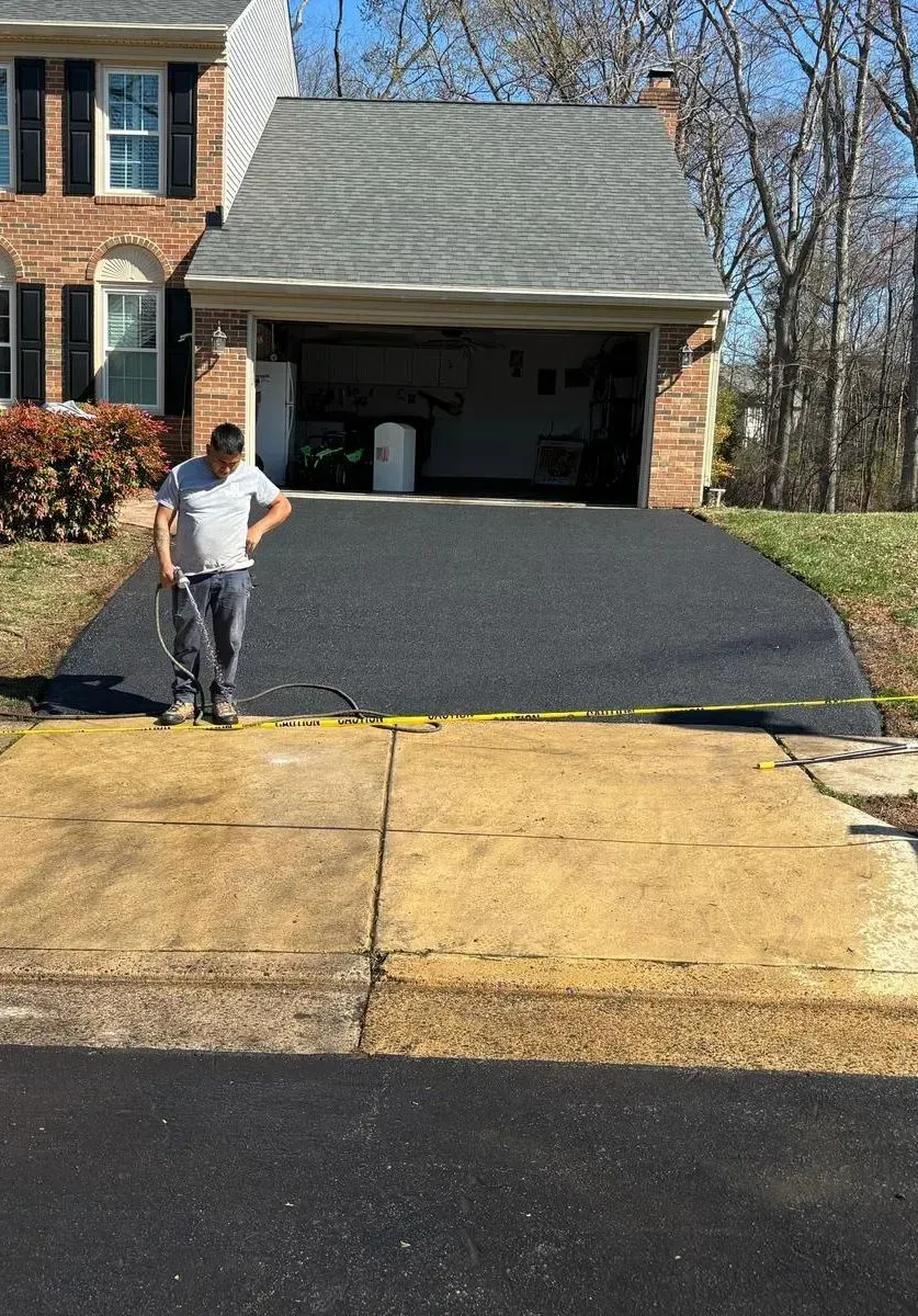 A man is standing in a driveway in front of a house.