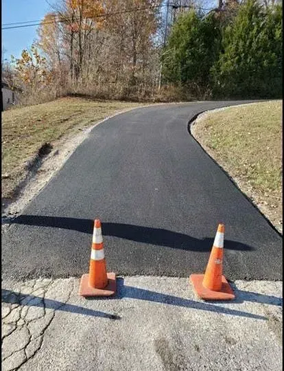 Two orange traffic cones are sitting on the side of a road.