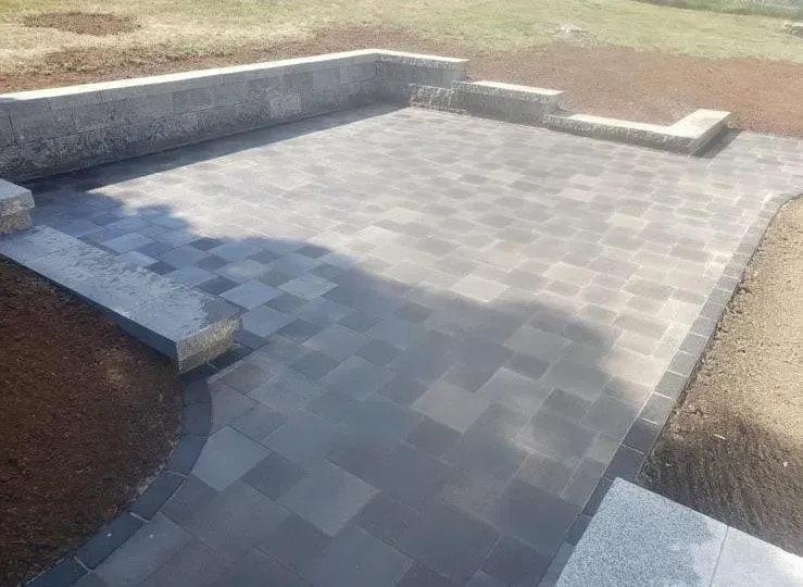 A patio with a stone wall and steps leading to it.