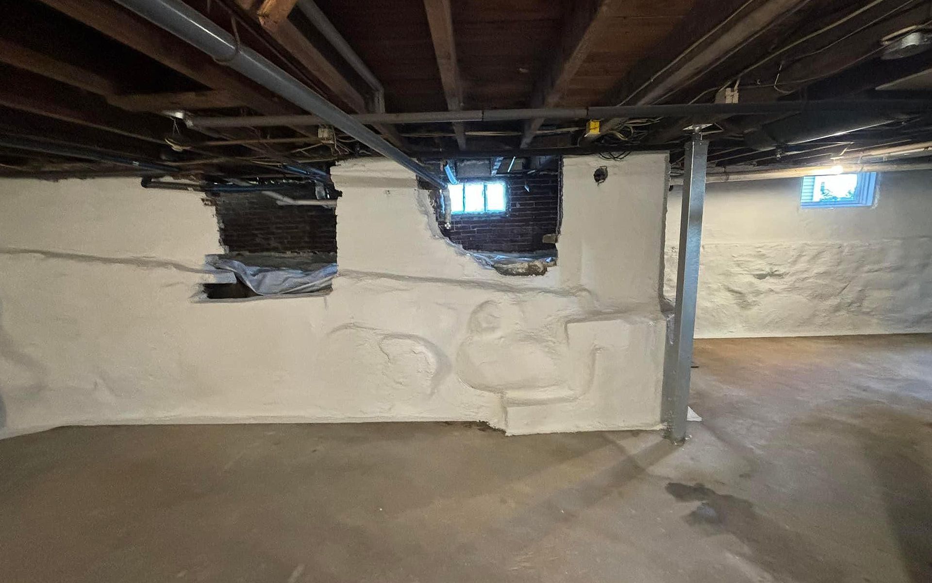 A basement with a hole in the wall and a window.