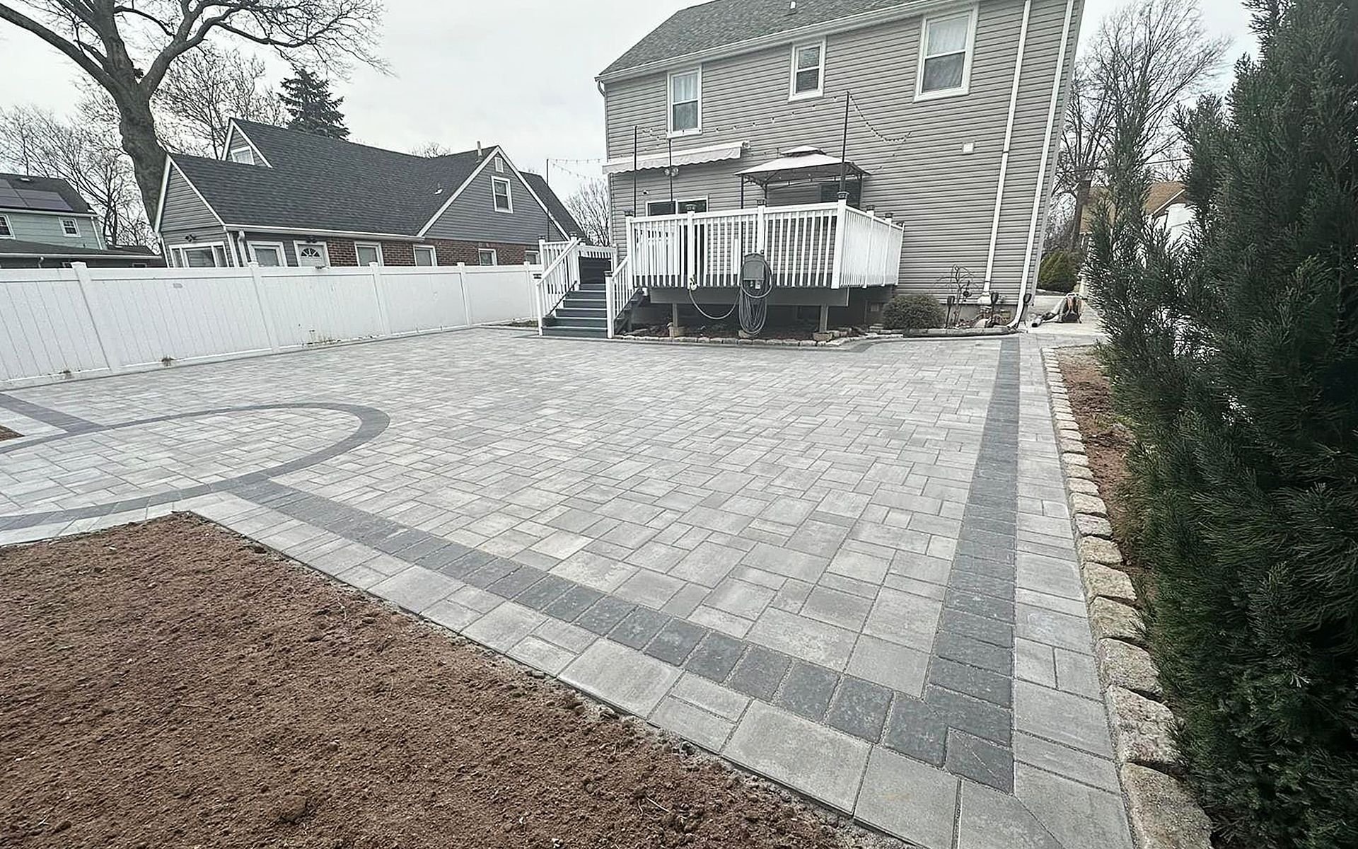 A large house with a patio and a brick driveway in front of it.