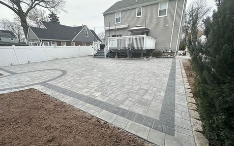 A large house with a patio and a brick driveway in front of it.