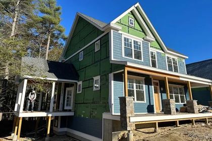 a green and blue house with a porch under construction 