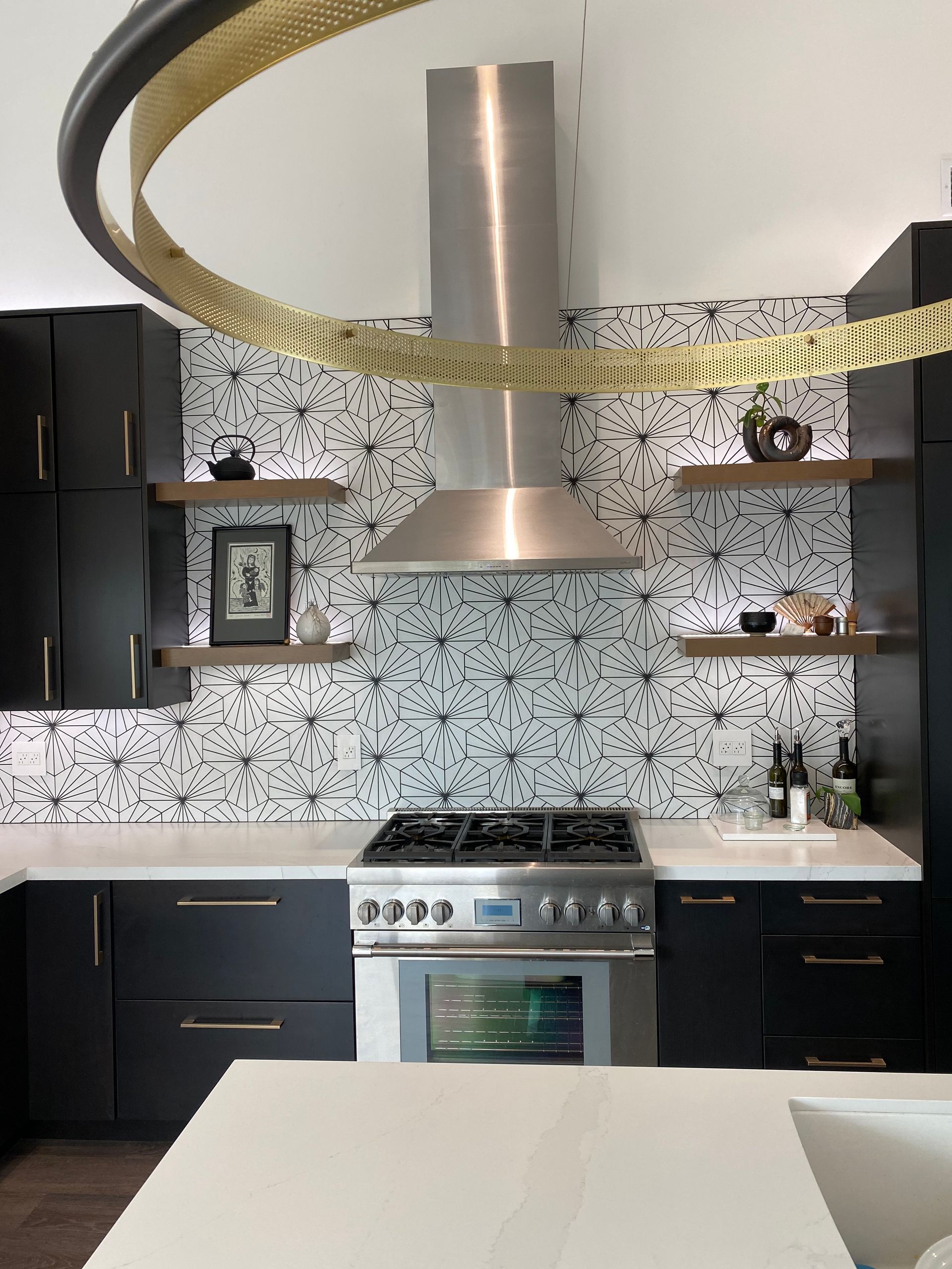 Modern kitchen with black cabinets, stainless range hood, and speckled backsplash