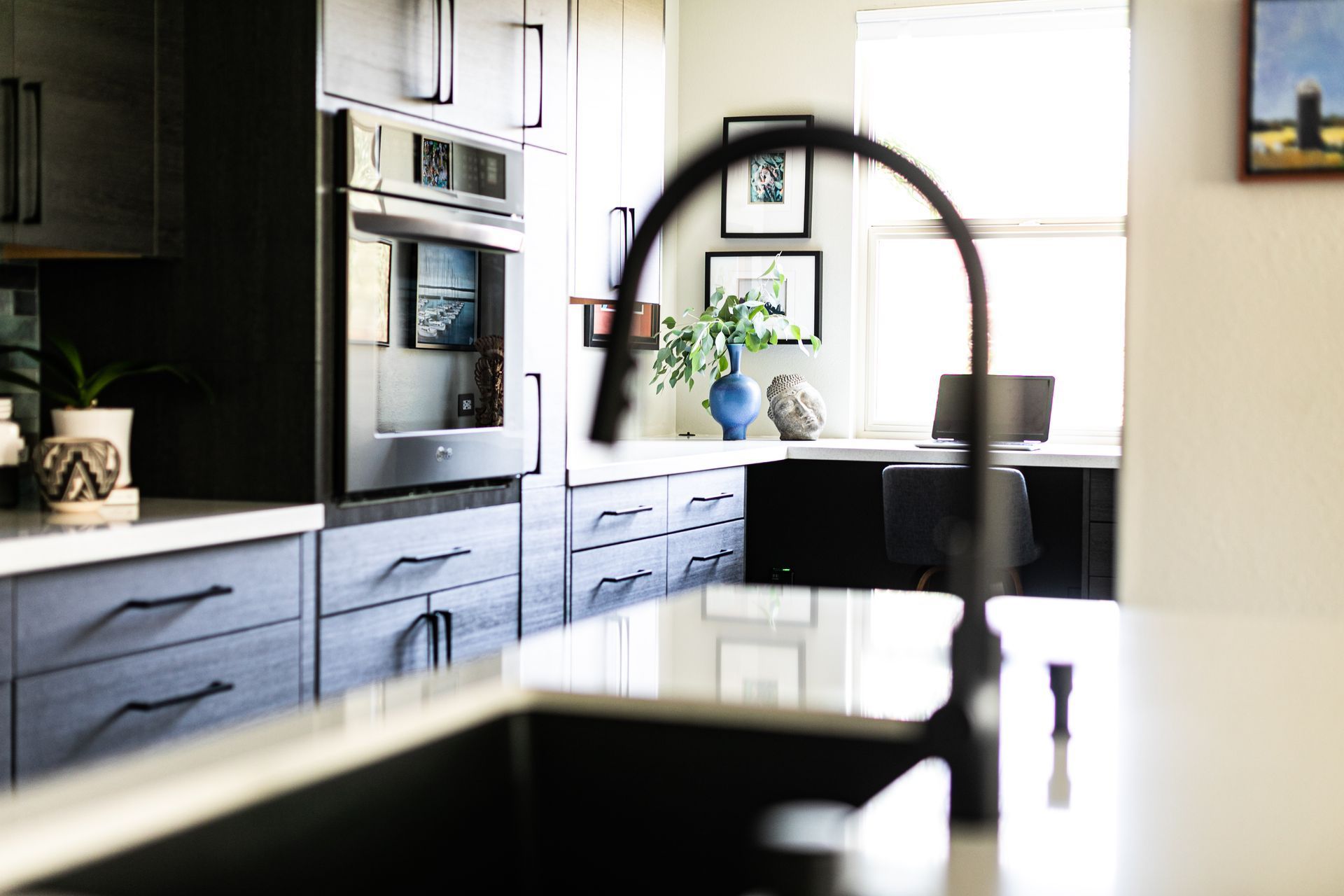 Modern kitchen with dark cabinets, built-in oven, and a dining table by a bright window