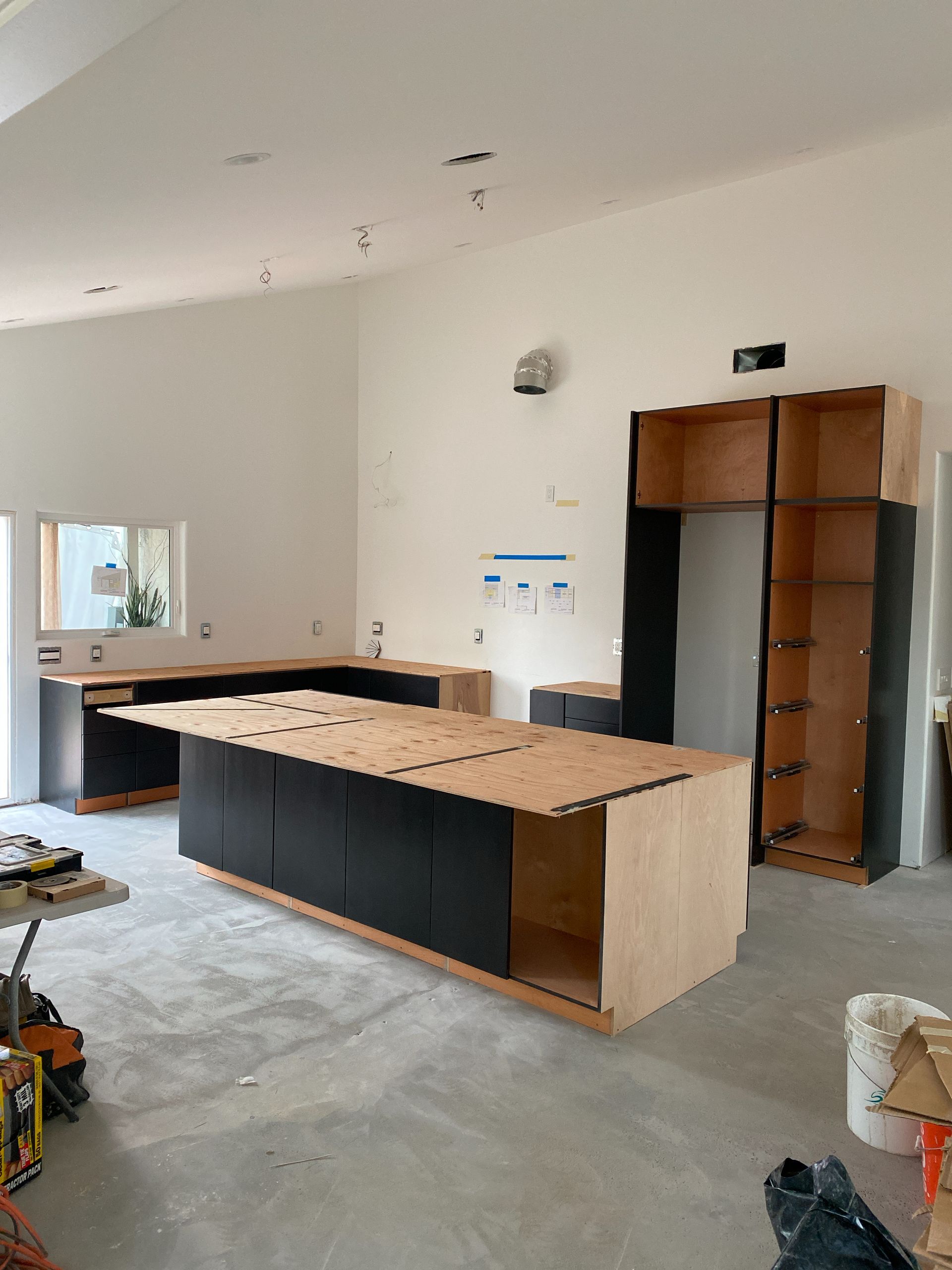 Kitchen under construction with unfinished cabinets, wood countertops, and a large island in a bright room