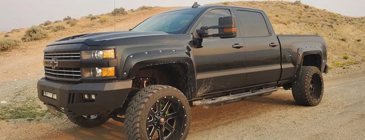 A black truck is parked on top of a dirt hill.