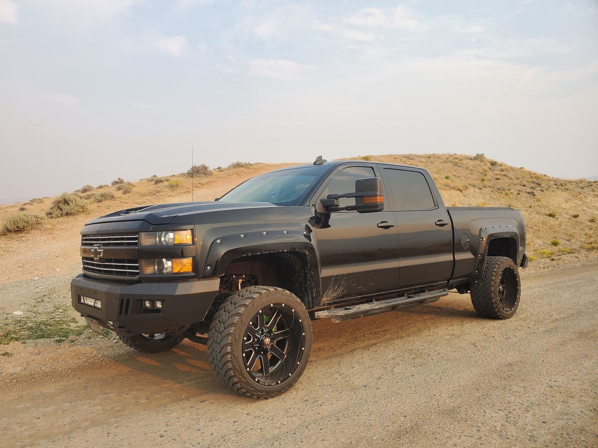 A black truck is parked on the side of a dirt road.