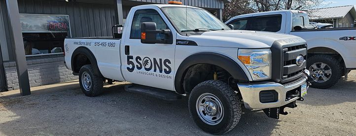 Two white trucks are parked next to each other in front of a building.
