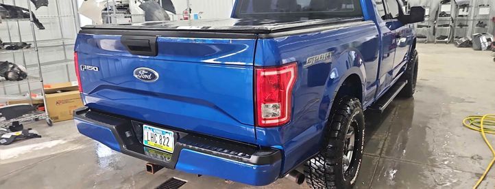 A blue ford f150 truck is parked in a garage.