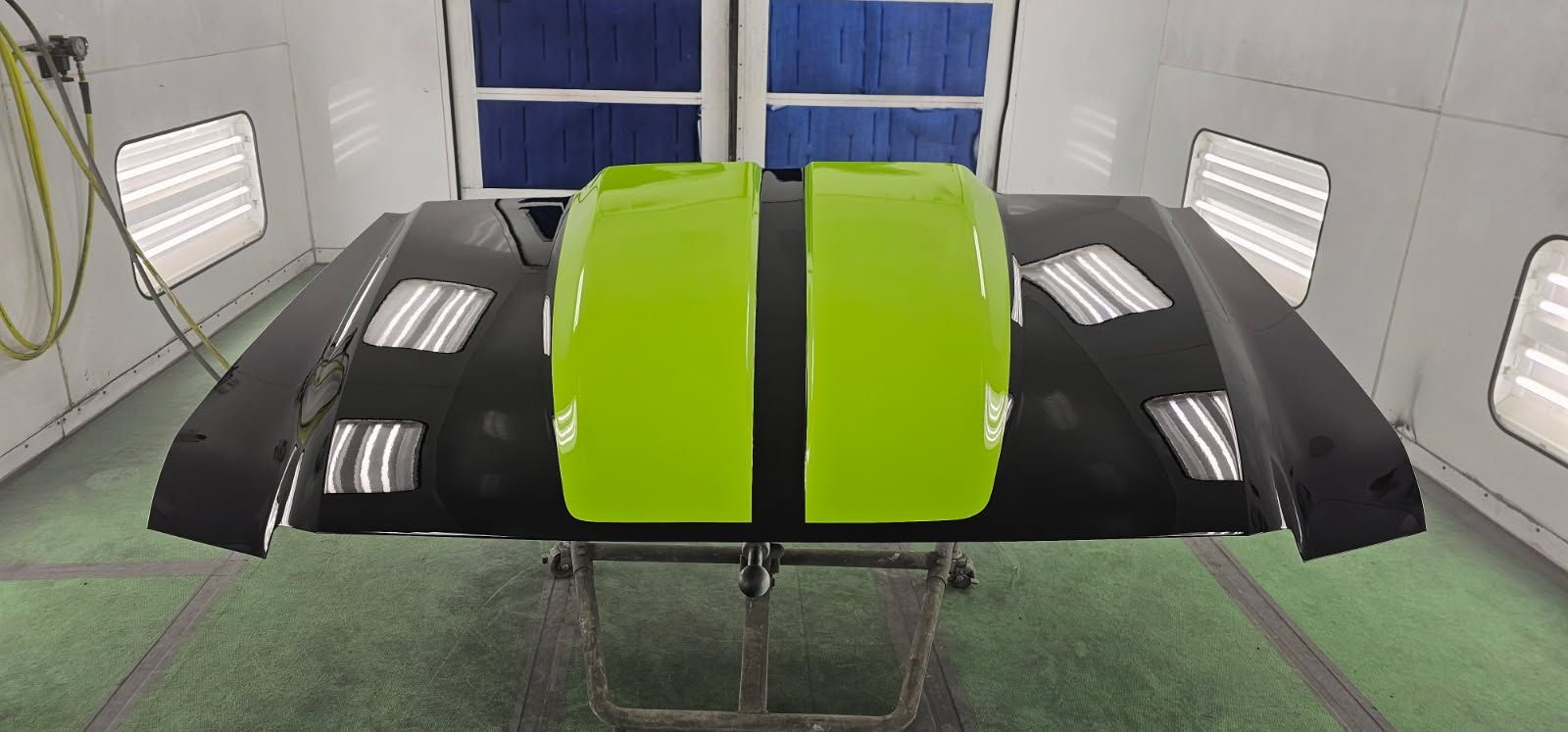 An empty paint booth with a green floor and white walls