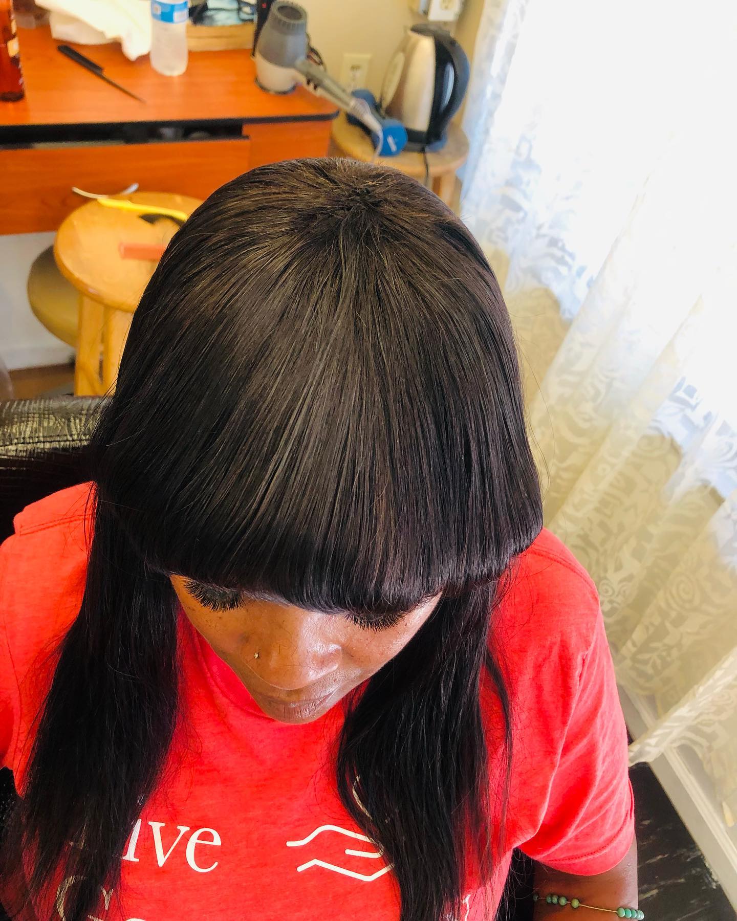 African American woman with head of straight black hair looking down.