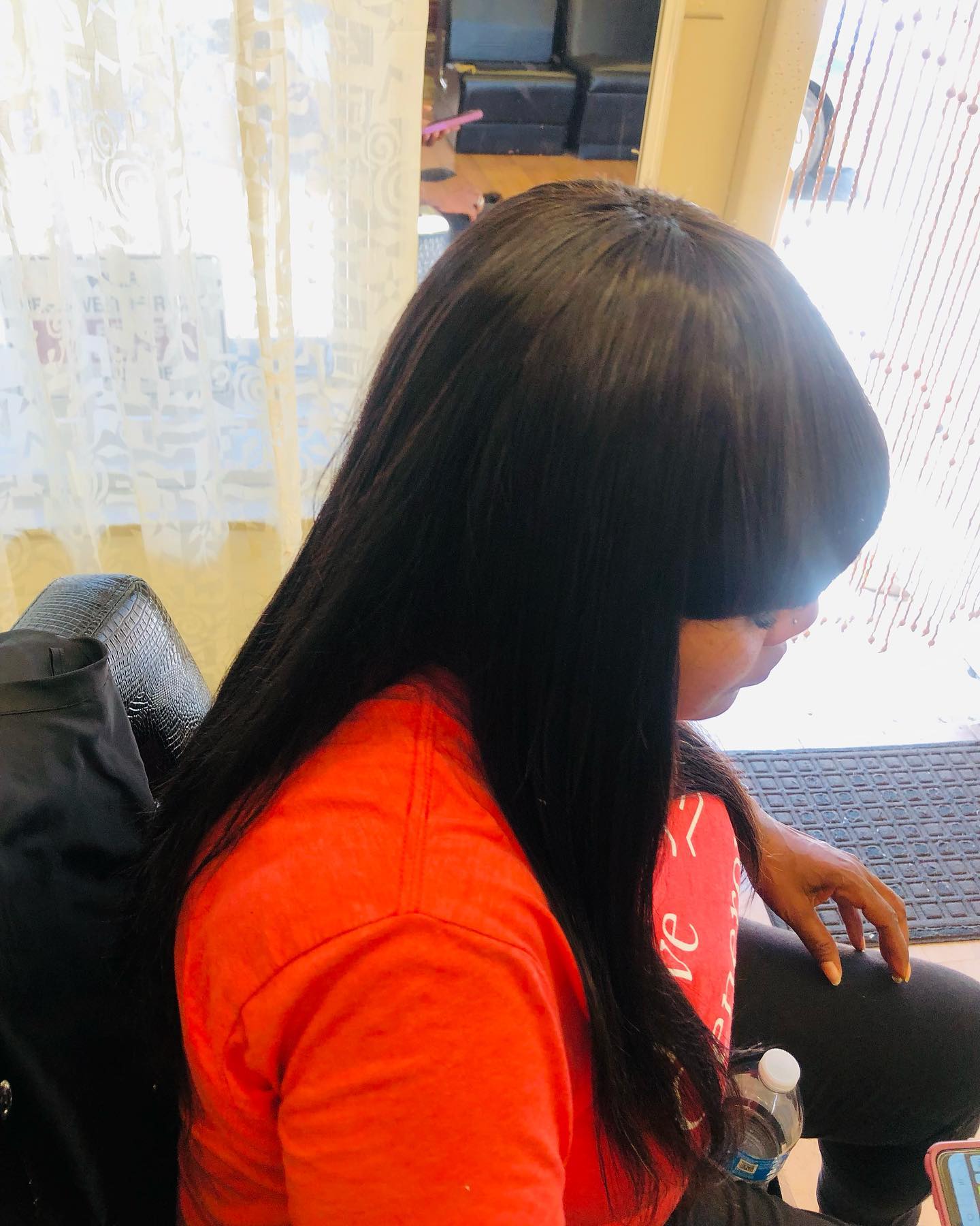 Side view of African American woman with black straight hair and bangs.