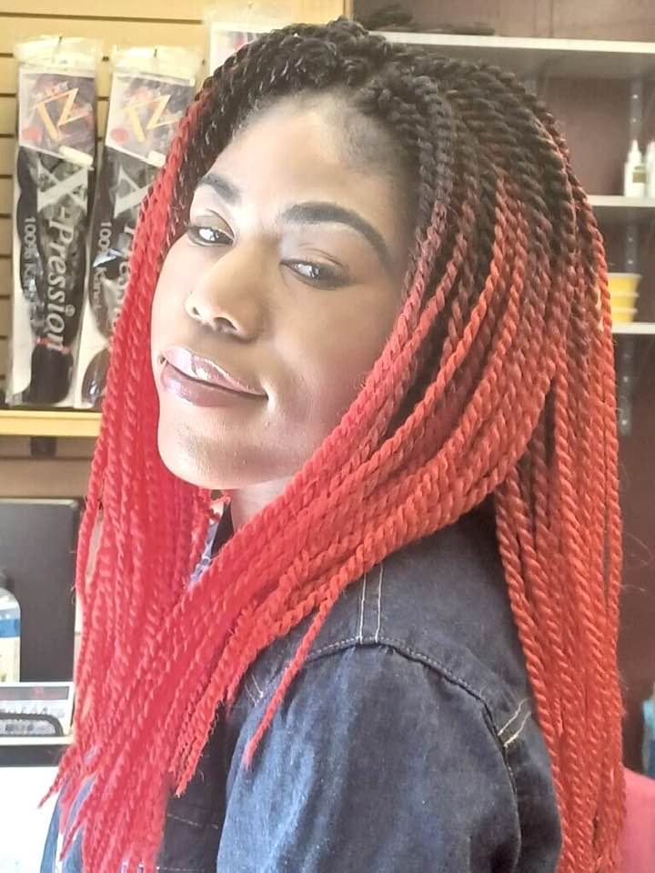 Young African American woman with long red braided extensions looking at the camera in profile.