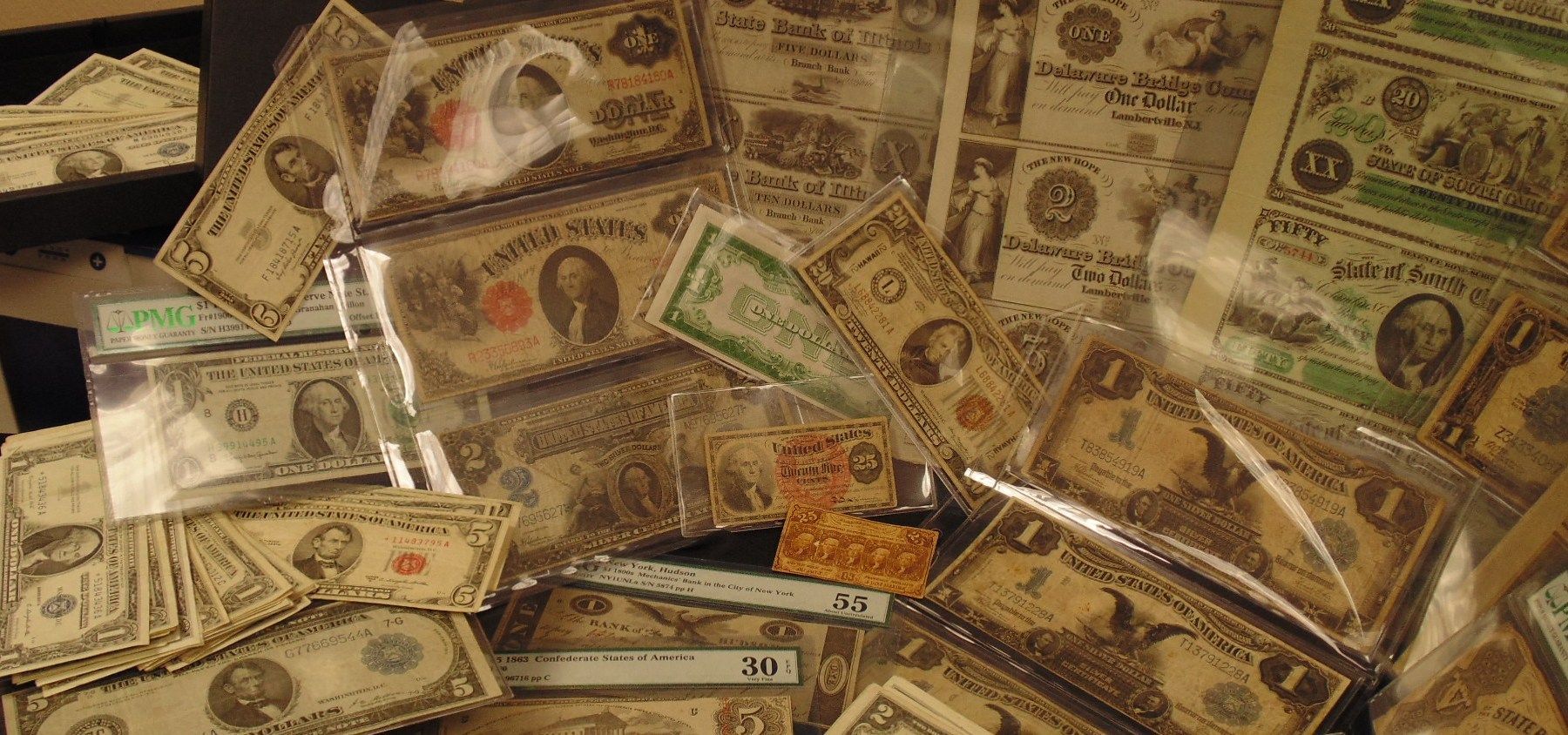 Collection of old United States one dollar bills, some in protective sleeves.