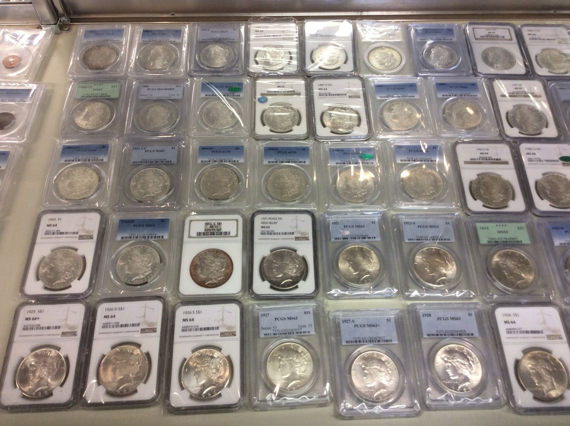 Display of graded silver coins in protective cases, likely for sale at a coin show.