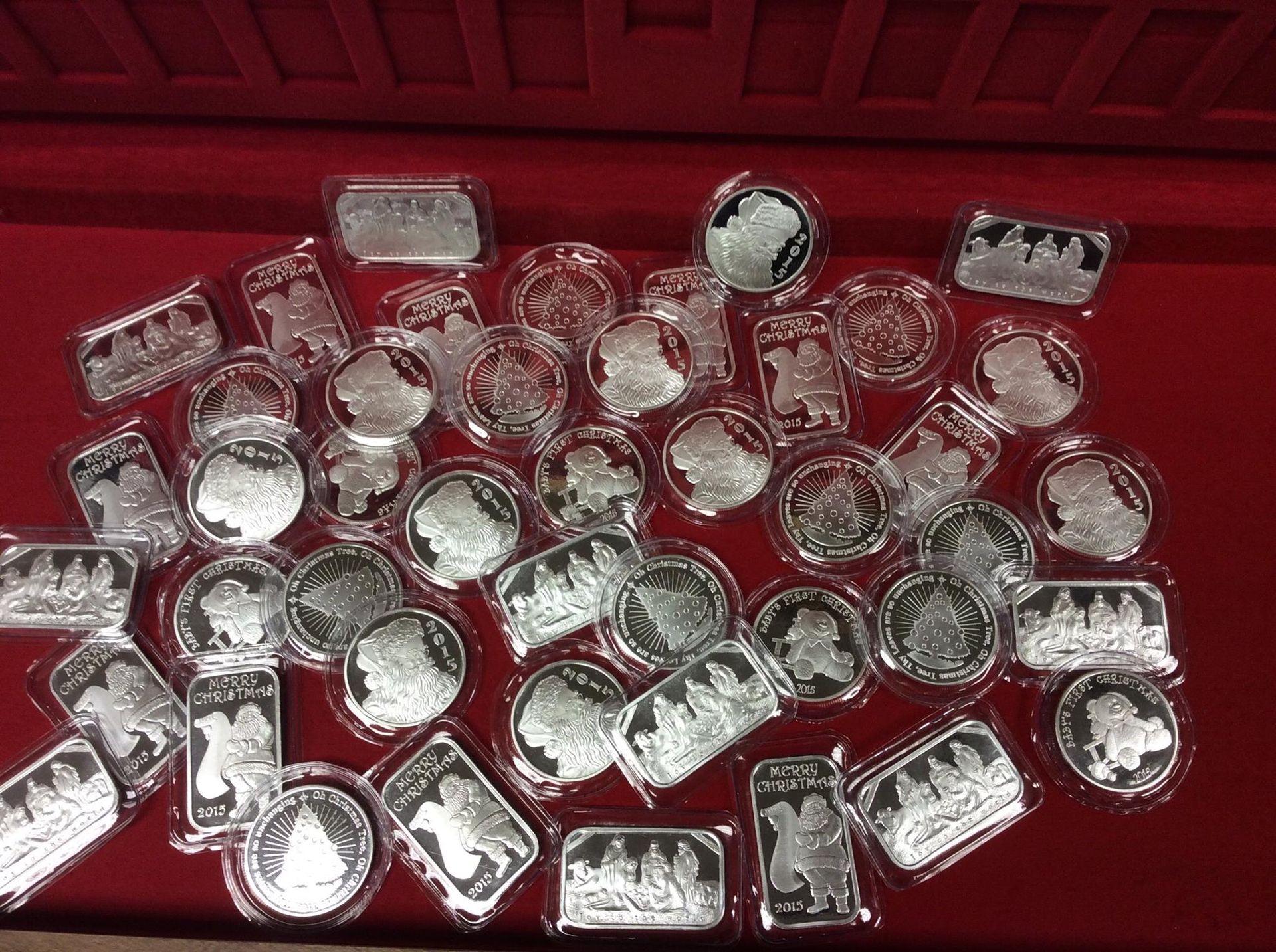 Silver coins and bars scattered on a red surface.