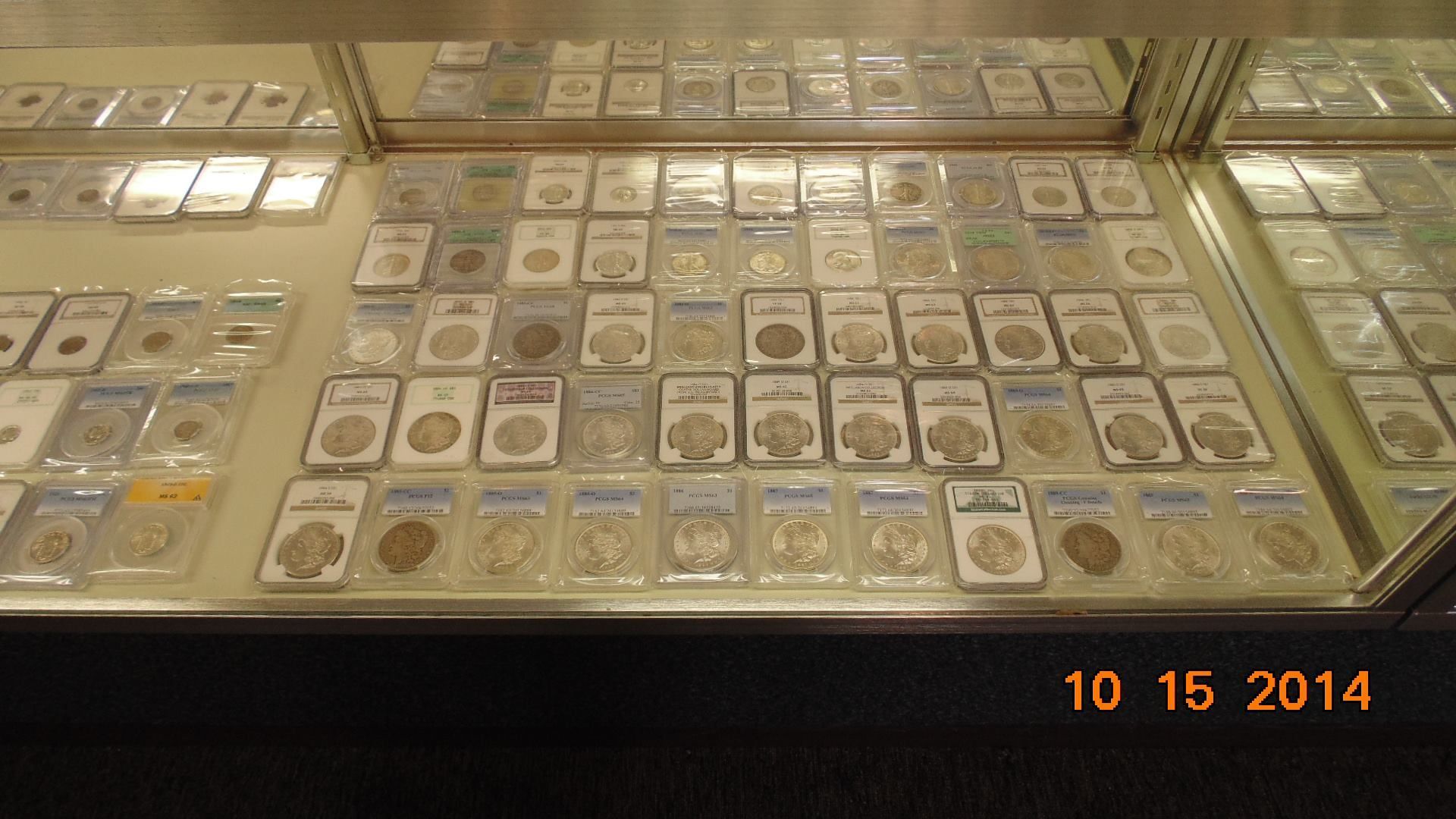 Coins displayed in protective cases within a glass display cabinet. Dated October 15, 2014.