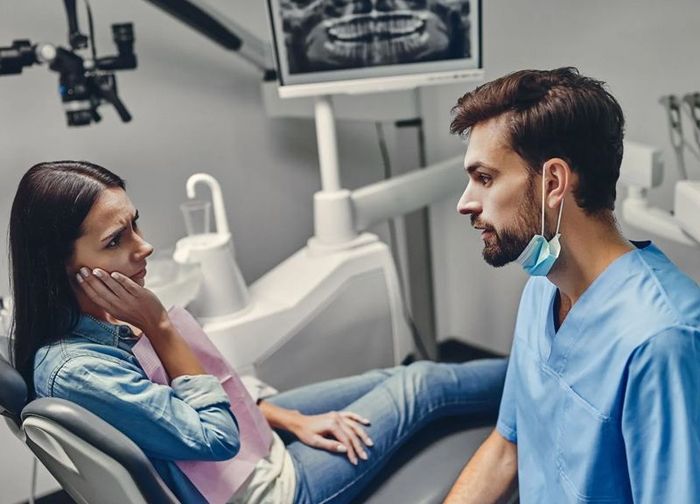 A woman is sitting in a dental chair talking to a dentist.