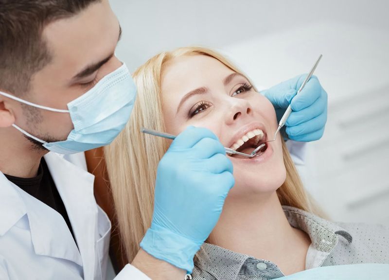 A woman is getting her teeth examined by a dentist.