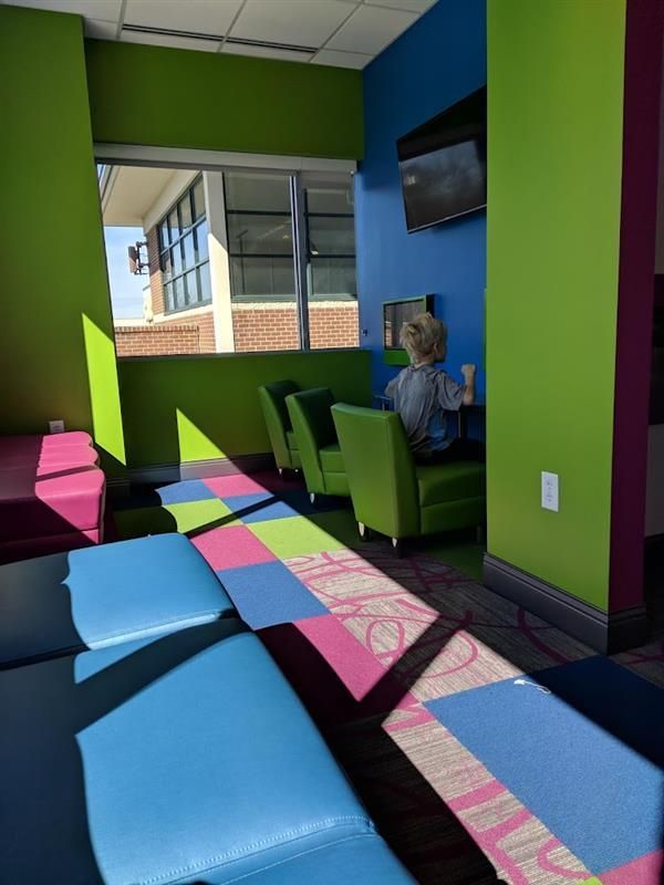 A person is sitting in a chair in a room with colorful chairs