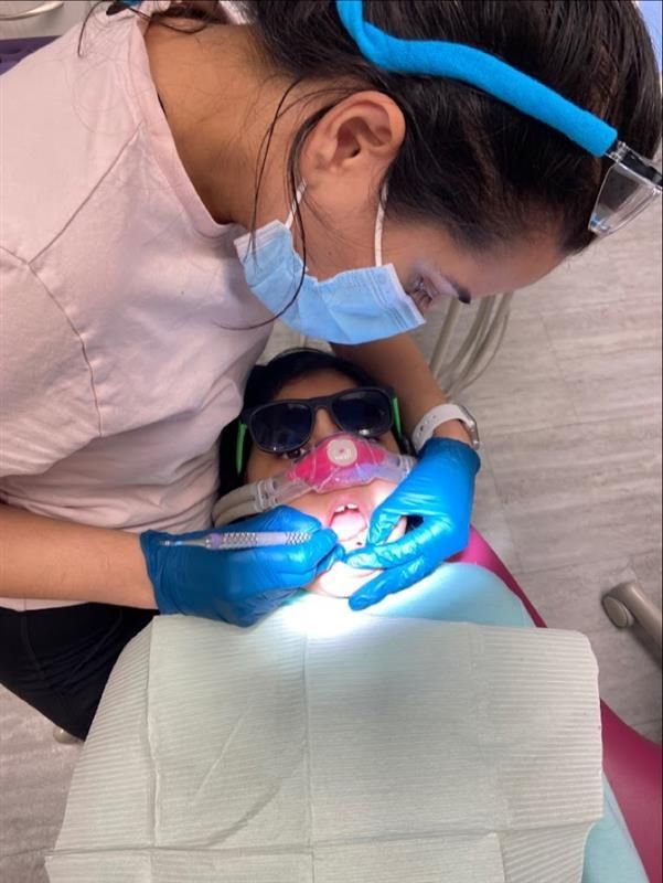 A female dentist is examining a child's teeth