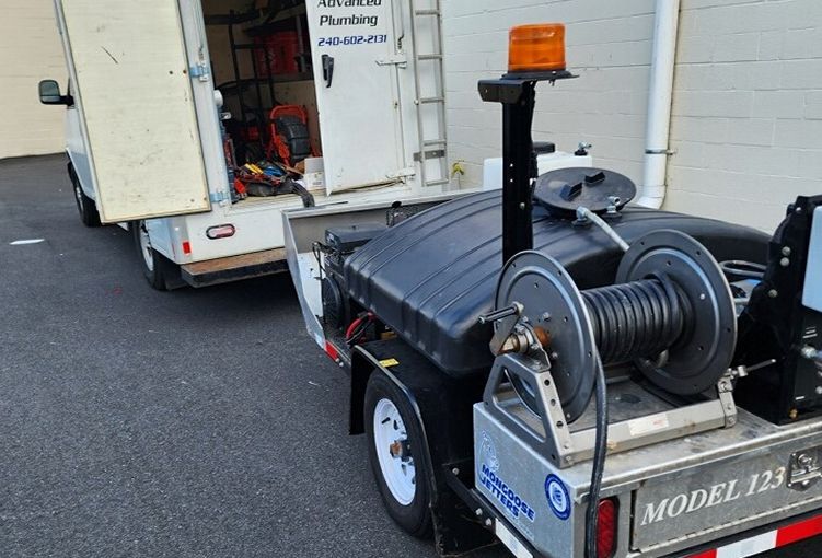 A trailer with a hose reel attached to it is parked next to a truck.