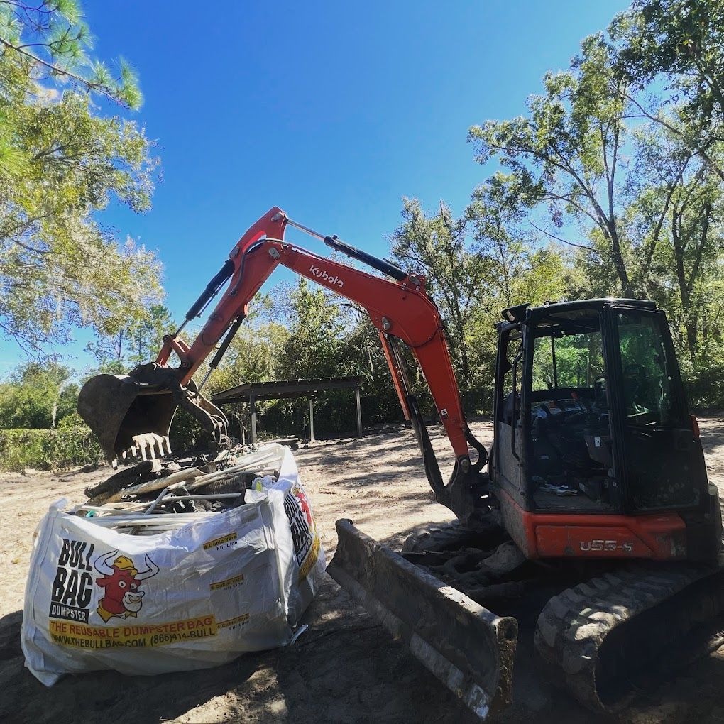 An excavator is carrying a bag that says ak bag on it