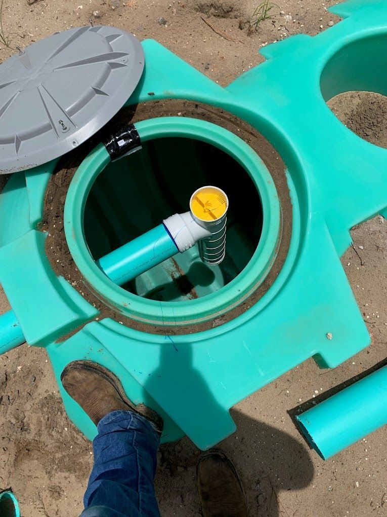A person is standing next to a green septic tank with the lid open