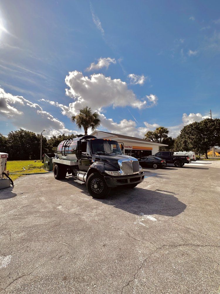 A black truck is parked in a parking lot in front of a building.