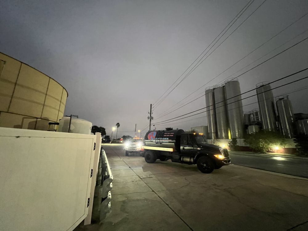 A tow truck is driving down a street at night.