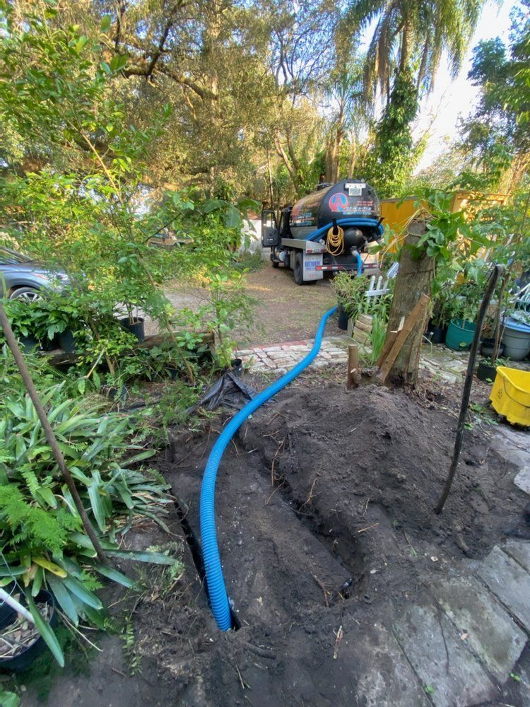 A blue hose is connected to a truck in a yard.