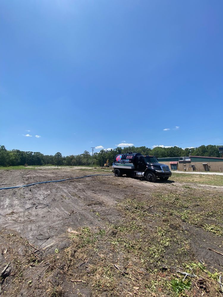A black truck is parked in the middle of a dirt field.