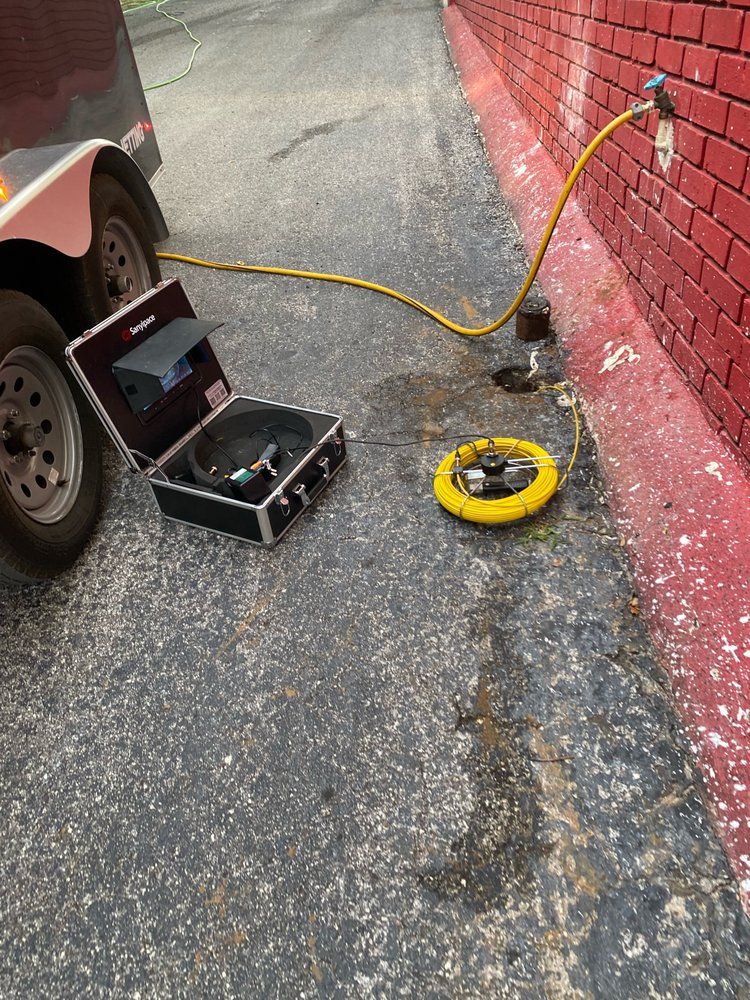 A hose is attached to a brick wall next to a car.