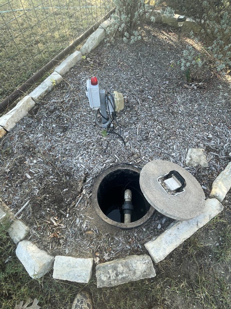A manhole cover is sitting in the middle of a gravel area.