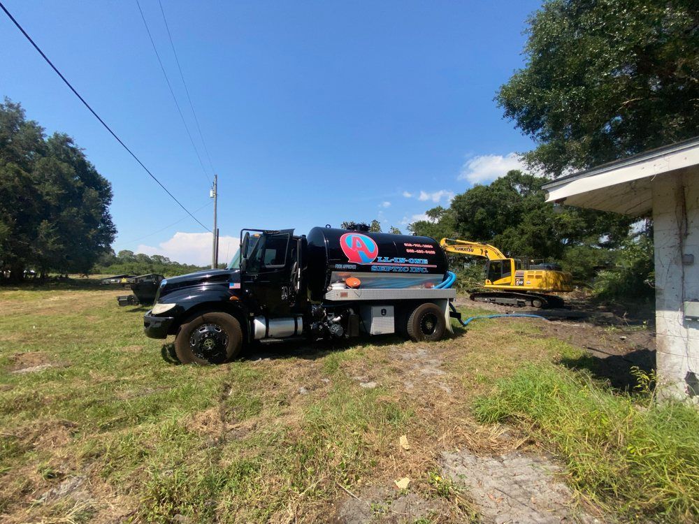 A black truck is parked in a grassy field next to a yellow excavator.