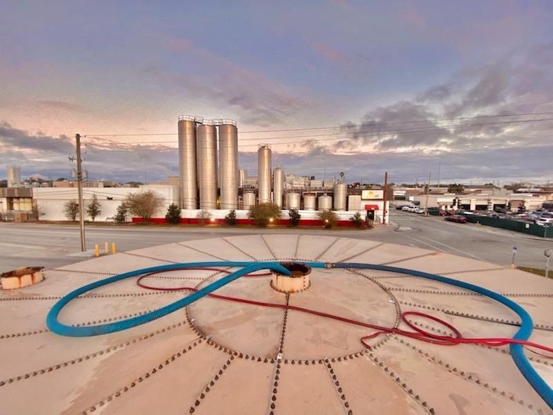 An aerial view of a large circular structure with a factory in the background.